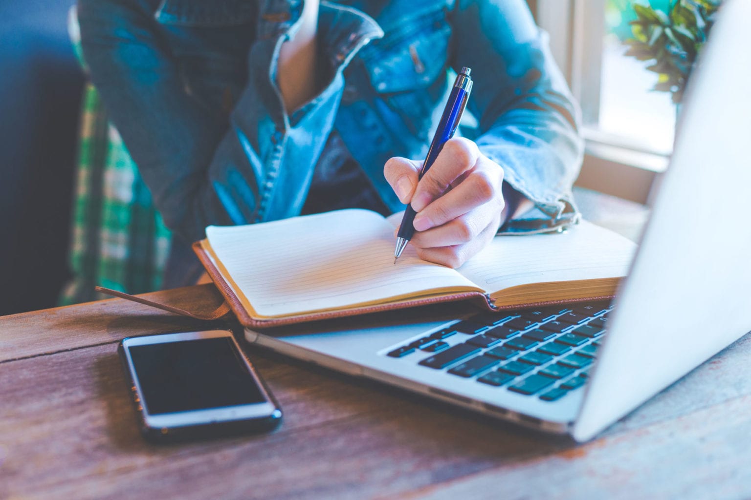 photo showing a woman writing a plan into a notebook