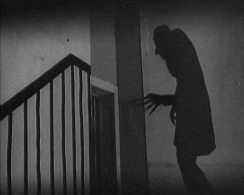 gif of the long, tall shadow of Nosferatu from the original black and white movie, reaching a clawed hand toward a door